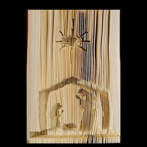 May include: A book folded into a three-dimensional art piece depicting the nativity scene with a star above the stable. The scene is made of beige paper.