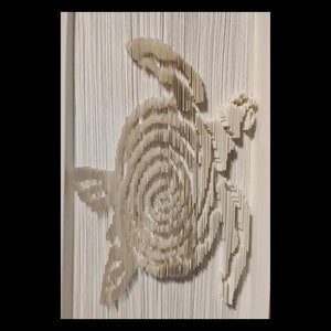 May include: A white paper book folded into the shape of a turtle. The turtle is facing right and has a detailed shell.