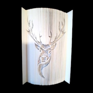 Op de afbeelding: Een boekkunst sculptuur van een hertenkop, gemaakt door de pagina's van een boek te vouwen. De geweien van het hert zijn wijd gespreid en het hoofd is naar voren gericht.