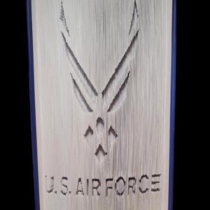 Puede incluir: Un libro con el logotipo de la Fuerza A&eacute;rea de los Estados Unidos recortado en las p&aacute;ginas. El logotipo es una estrella estilizada con alas. Las palabras "U.S. AIR FORCE" est&aacute;n recortadas debajo del logotipo.