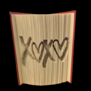 Op de afbeelding: Een boek met de woorden "XOXO" en twee harten die uit de pagina's zijn geknipt. Het boek is rood aan de buitenkant en wit aan de binnenkant.