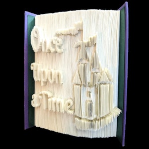 May include: A white book with the words "Once Upon a Time" folded into the pages. The book is open and a castle is folded into the pages.