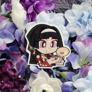 May include: A sticker featuring a cartoon character with black hair, red and white clothing, and pink cheeks. The character is holding a small, round, beige object. The sticker is surrounded by purple and blue flowers.
