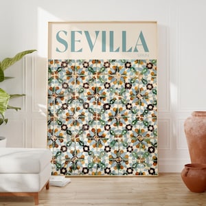 May include: A framed print featuring the word "SEVILLA" in teal above the word "SPAIN". The print displays a pattern of colorful, floral tiles in shades of blue, brown, and green. The print is displayed in a room with terracotta vases and a white ottoman.