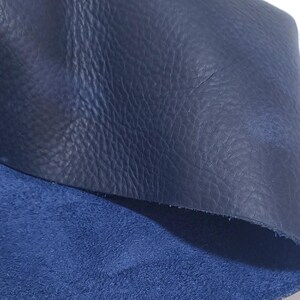 Pu&ograve; includere: Primo piano di due pezzi di pelle blu navy. Il pezzo superiore ha una superficie strutturata e granulosa, mentre il pezzo inferiore ha una consistenza pi&ugrave; morbida, simile alla pelle scamosciata. La pelle &egrave; di una tonalit&agrave; blu profonda e ricca.