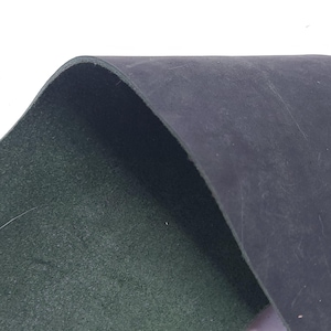 Pu&ograve; includere: Primo piano di un pezzo di pelle blu scuro, che rivela un interno verde. La pelle &egrave; leggermente curva, mostrando la sua consistenza e spessore. L'immagine evidenzia il contrasto tra l'esterno liscio e l'interno strutturato.