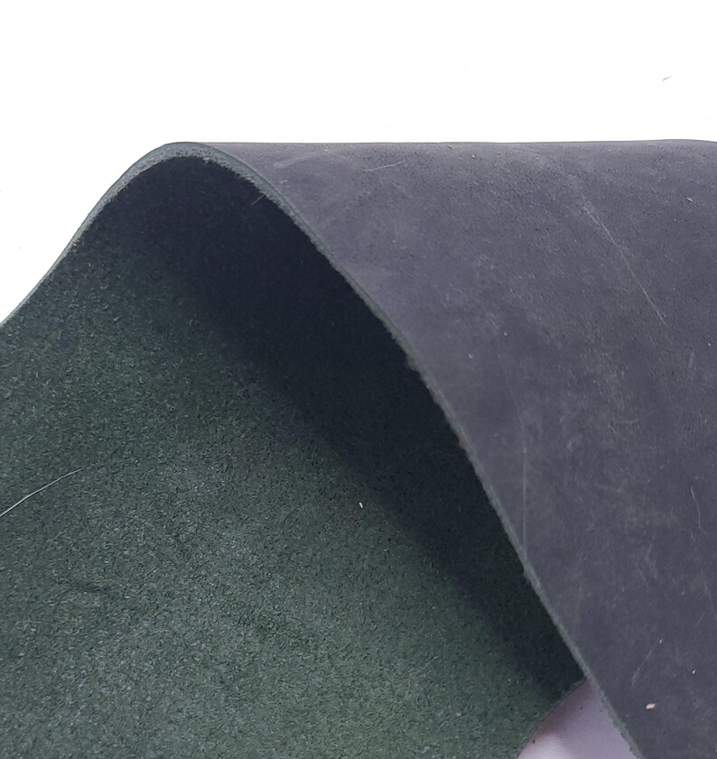 Pu&ograve; includere: Primo piano di un pezzo di pelle blu scuro, che rivela un interno verde. La pelle &egrave; leggermente curva, mostrando la sua consistenza e spessore. L'immagine evidenzia il contrasto tra l'esterno liscio e l'interno strutturato.