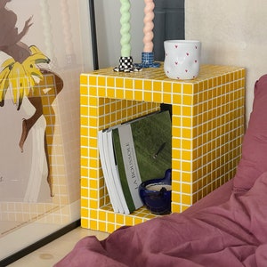 Comodino, tavolino giallo, tavolo piastrellato, tavolo con libri, arredamento per la casa.
