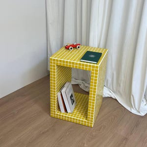 Comodino, tavolino giallo, tavolo piastrellato, tavolo con libri, arredamento per la casa.