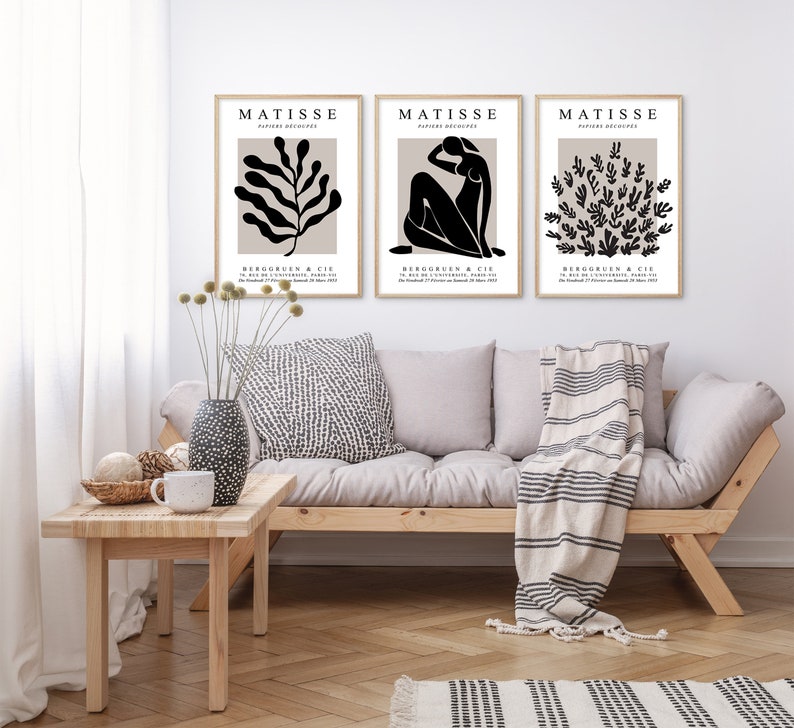 May include: Three black and white art prints with the text "MATISSE" and "BERGRUEN & CIE" in a beige frame. The prints feature abstract designs of a plant, a woman, and a cluster of leaves.