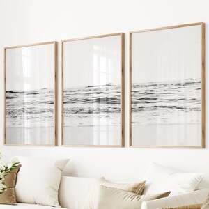 May include: Three framed black and white photographs of ocean waves crashing on a sandy beach.