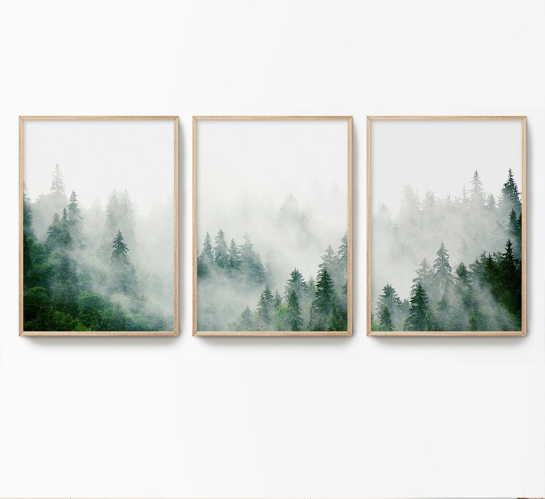 May include: A set of three framed prints featuring a misty forest scene with tall evergreen trees. The prints are in a minimalist style with a white background and a light wood frame.