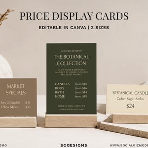 Peut inclure: Trois cartes de prix rectangulaires de couleur beige, vert foncé et crème, chacune maintenue par un support en bois clair. Les cartes présentent du texte imprimé incluant "MARKET SPECIALS", "THE BOTANICAL COLLECTION" et "BOTANICAL CANDLE".