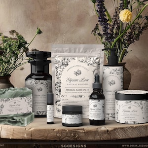 May include: A collection of Elysian Lore natural wellness products, including soap, body lotion, bath salts, and body scrub, arranged on a wooden surface. The products feature black and white labels with floral designs. A vase of flowers is in the background.