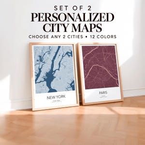 Peut inclure: Un ensemble de deux cartes de ville personnalisées dans des cadres en bois clair. L'impression de gauche montre une carte bleue de New York, celle de droite une carte bordeaux de Paris. Texte : SET OF 2 PERSONALIZED CITY MAPS CHOOSE ANY 2 CITIES 12 COLORS.