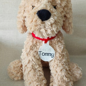 May include: A beige plush dog toy with a red collar and a white tag that says "Tommy".