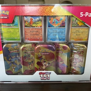 May include: A clear plastic display case with a red, yellow, and white Pokemon trading card game 5-pack. The case contains six small metal tins with Pokemon characters on them. The tins are labeled "Scarlet & Violet 151".