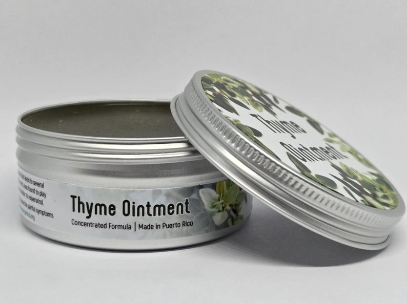 May include: A round silver metal tin containing Thyme Ointment with a concentrated formula. The lid features a green thyme leaf pattern and the text Thyme Ointment. The side label includes the text Thyme Ointment, Concentrated Formula, and Made in Puerto Rico.