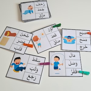 May include: Educational flashcards with Arabic words and illustrations. Each card features a picture and corresponding word, secured with colorful clothespins. The cards depict various actions and objects, ideal for early learning.