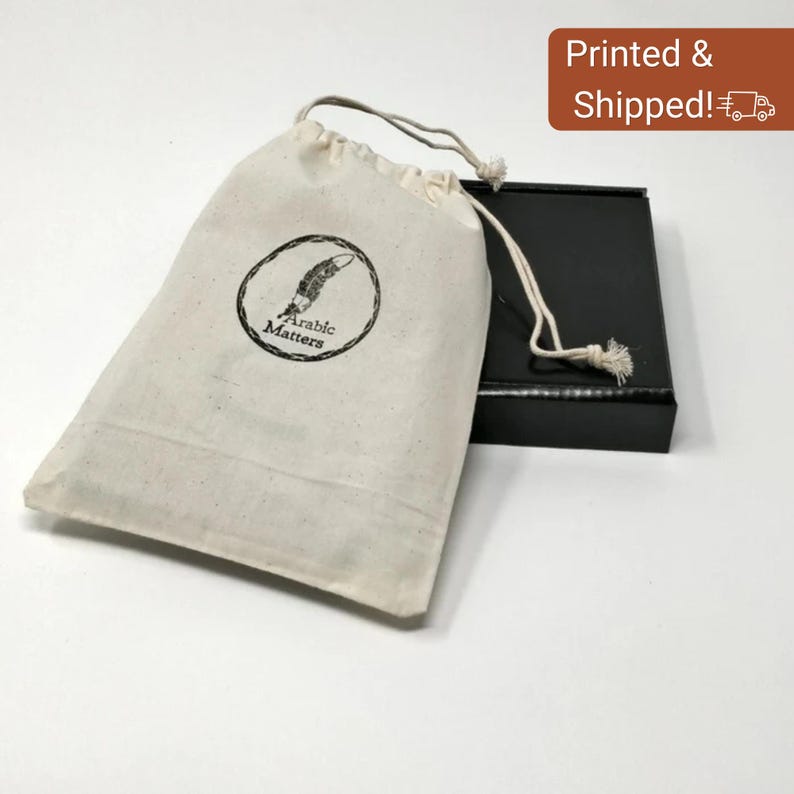 May include: A natural canvas drawstring bag with a black circular logo that reads "Arabic Matters" and a feather illustration. A black box is next to the bag. The words "Printed & Shipped!" are in a brown box.