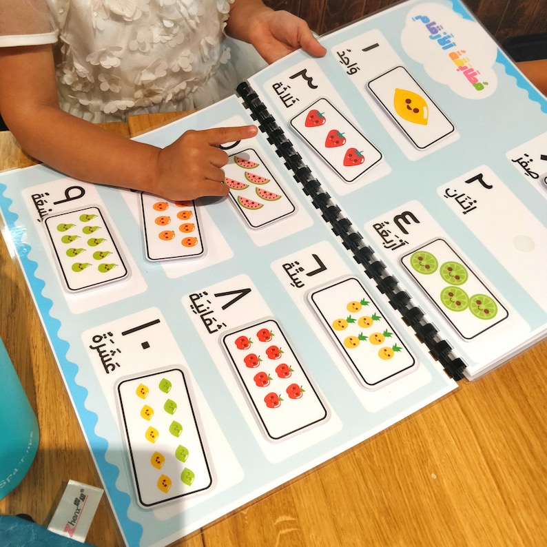 May include: A spiral-bound educational book with colorful illustrations of fruits and numbers. The pages display Arabic numerals and corresponding images of fruits like strawberries, watermelons, and lemons. The book is designed for early learning.