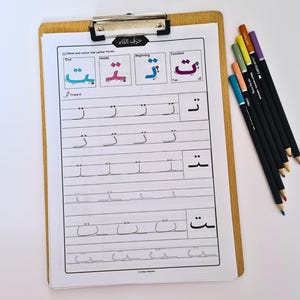 Könnte beinhalten: Ein Holz-Klemmbrett enthält ein Arbeitsblatt mit arabischen Buchstaben-Nachzeichnungsübungen und farbigen Beispielen. Das Arbeitsblatt zeigt den arabischen Buchstaben „taa“ in verschiedenen Formen. Ein Satz von sieben Farbstiften liegt auf der rechten Seite.