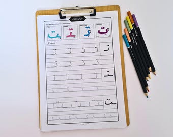 May include: A wooden clipboard holds a worksheet with Arabic letter tracing exercises and colored examples. The worksheet features the Arabic letter "taa" in different forms. A set of seven colored pencils rests on the right side, ready for use.