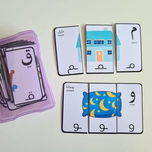 May include: Educational puzzle cards with Arabic script and illustrations. The cards show a house and a pillow, with Arabic letters. A purple plastic container holds the remaining cards. Metric measurements are used.