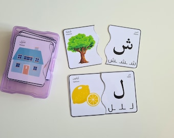 May include: A set of educational puzzle cards in a clear purple case. The cards feature colorful illustrations of a house, tree, and lemon, along with Arabic script. The puzzle pieces are designed to fit together, promoting learning and play.