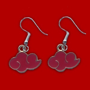 May include: A pair of silver earrings with pink cloud charms. The clouds are outlined in gold.