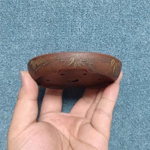 May include: A brown ceramic bonsai pot with a decorative design of gold leaves around the rim.