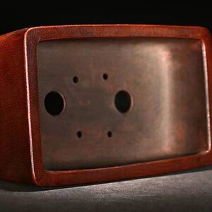 May include: A rectangular, dark red bonsai pot with two drainage holes. The pot is made of ceramic and has a smooth, glossy finish.