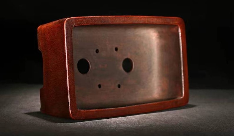 May include: A rectangular, dark red bonsai pot with two drainage holes. The pot is made of ceramic and has a smooth, glossy finish.