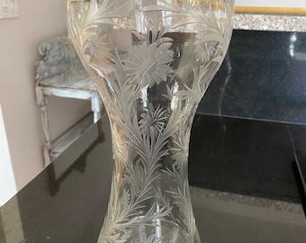 May include: A clear glass vase with an etched floral design. The vase has a wide mouth and a narrow base.