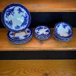 Könnte beinhalten: Ein Set aus blauen und weißen Porzellantellern und Schalen mit einem Blumenmuster. Die Teller sind auf einem Ständer gestapelt und die Schalen liegen nebeneinander.
