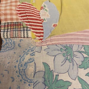 May include: A patchwork quilt block with a variety of fabrics, including gingham, stripes, and floral patterns. The block is made up of several different pieces of fabric sewn together to create a unique design.