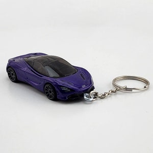 May include: A purple toy car keychain with a silver chain and ring. The car is a detailed replica of a McLaren Senna.