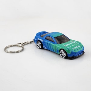 May include: A blue and green Mazda RX-7 keychain with Falken Tires branding. The keychain features a silver key ring.