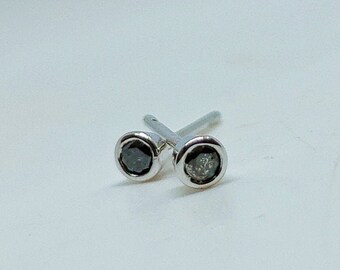 May include: A pair of silver stud earrings with a black diamond on one and a clear diamond on the other.