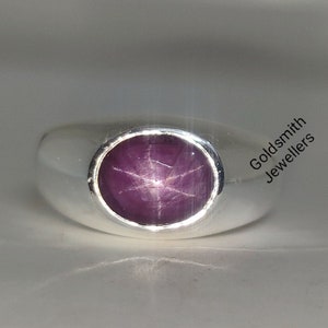 Op de afbeelding: Een zilveren ring met een paarse stervormige edelsteen in het midden. De ring is van klassieke stijl met een afgeronde band.