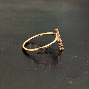 May include: A gold ring with a delicate band and a vertical design of small diamonds. The ring is set against a black background.