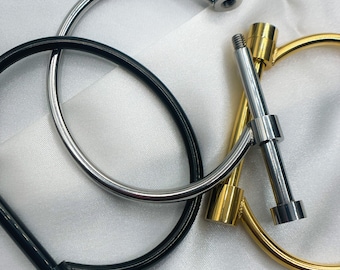 May include: Three metal bracelets with a simple, minimalist design. The bracelets are made of silver, gold, and black metal. Each bracelet has a small, round knob at the end.