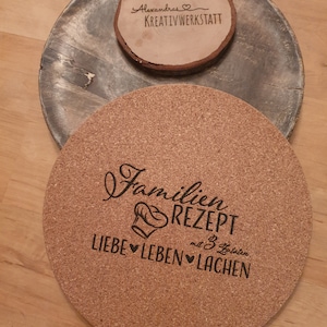 Könnte beinhalten: Ein runder Korkuntersetzer mit dem Text "Familien Rezept mit 3 Zutaten Liebe ♥ Leben ♥ Lachen" in schwarzer Schrift. Der Untersetzer liegt auf einer Holzoberfläche.