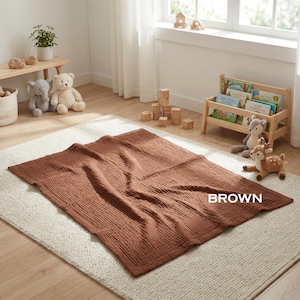 K&ouml;nnte beinhalten: Eine rechteckige braune Decke mit einer strukturierten, geknitterten Stoffoberfl&auml;che. Die Decke liegt flach auf einem hellen Teppich. Das Wort BROWN ist in wei&szlig;en Gro&szlig;buchstaben auf der unteren rechten Seite der Deckenoberfl&auml;che aufgedruckt.