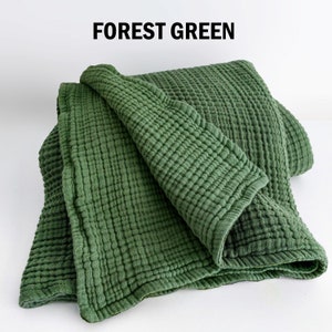 May include: A forest green blanket with a textured, crinkled appearance. The blanket is folded over, showcasing its soft, layered design. The words "FOREST GREEN" are printed in bold, black letters at the top.