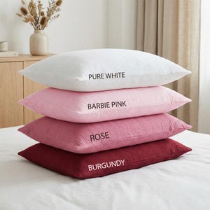 Pode incluir: Quatro almofadas empilhadas em tons de rosa e vermelho. A almofada superior &eacute; branca, com a etiqueta "PURE WHITE". Abaixo est&atilde;o almofadas em "BARBIE PINK", "ROSE" e "BURGUNDY".