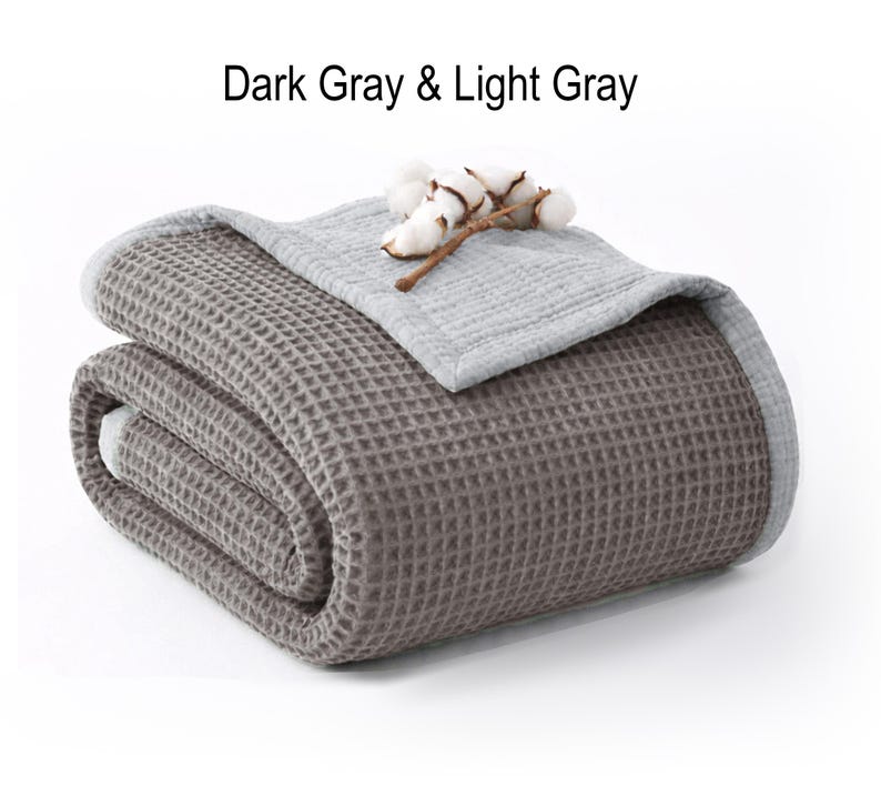 May include: A folded dark gray waffle-weave blanket with a light gray border and top layer. The blanket is adorned with a sprig of cotton. The text "Dark Gray & Light Gray" is displayed at the top.