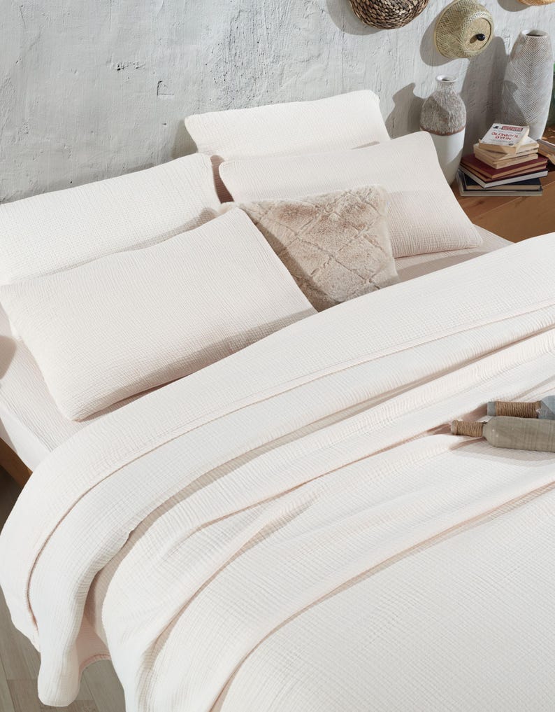 May include: A white waffle-textured bedding set with a fluffy faux fur throw pillow. The bedding is arranged on a bed with a wooden headboard.