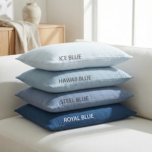 Pode incluir: Quatro almofadas azuis empilhadas em um sof&aacute; branco. A almofada superior &eacute; azul gelo, seguida por azul Hava&iacute;, azul a&ccedil;o e azul royal. Cada almofada tem uma superf&iacute;cie texturizada e o nome da cor impresso.