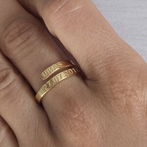 Peut inclure: Une bague en or avec les mots "UBAS" et "27.07.2019" gravés dessus. La bague est portée au doigt d'une personne.
